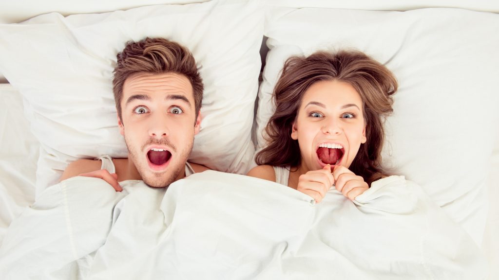 Surprised funny couple in love lying in the bed